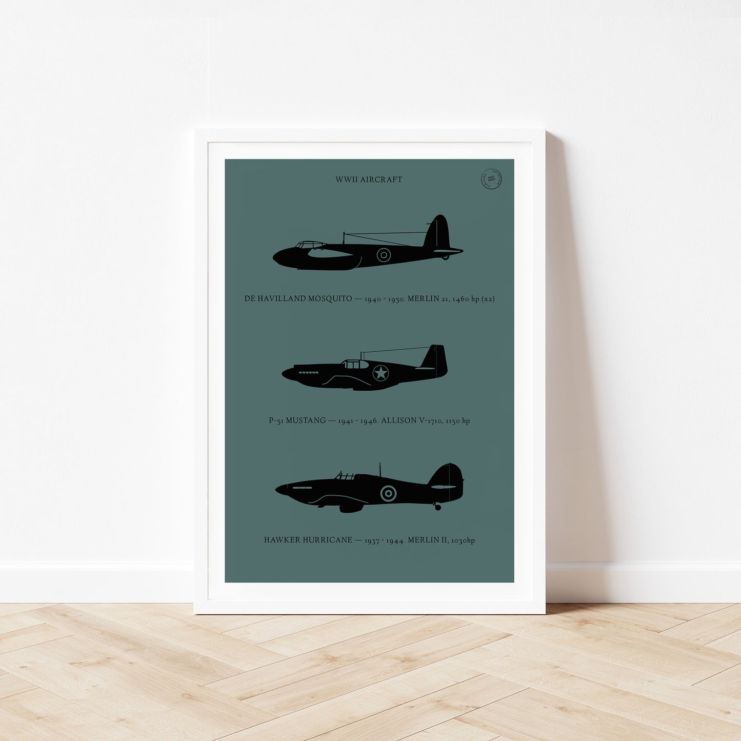 Framed poster standing on wood flooring, leaning against a white wall. It shows the profiles of three WW2 period aeroplanes in a black silhouette style over a dark green background
