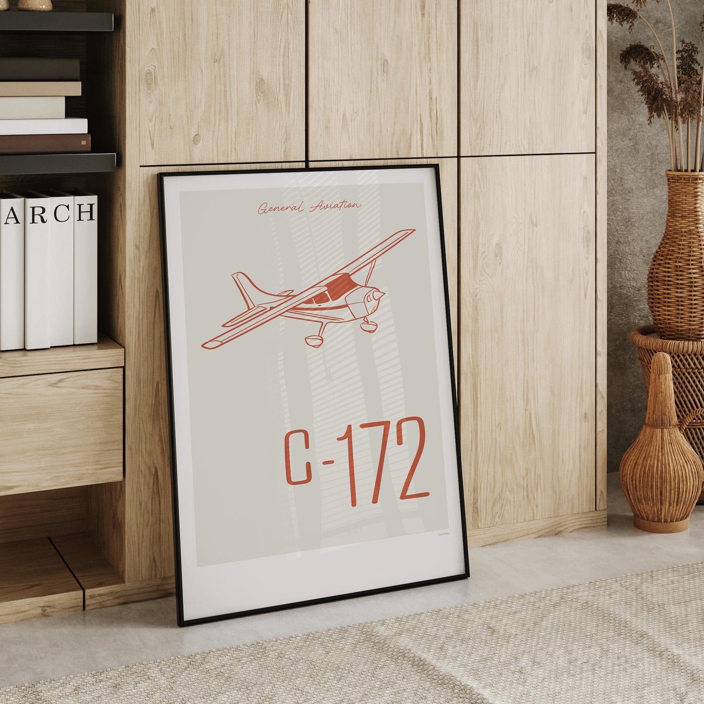 Large framed poster leaning against a cupboard in a home office showing a light aircraft illustration with the words General Aviation and C-172 in red