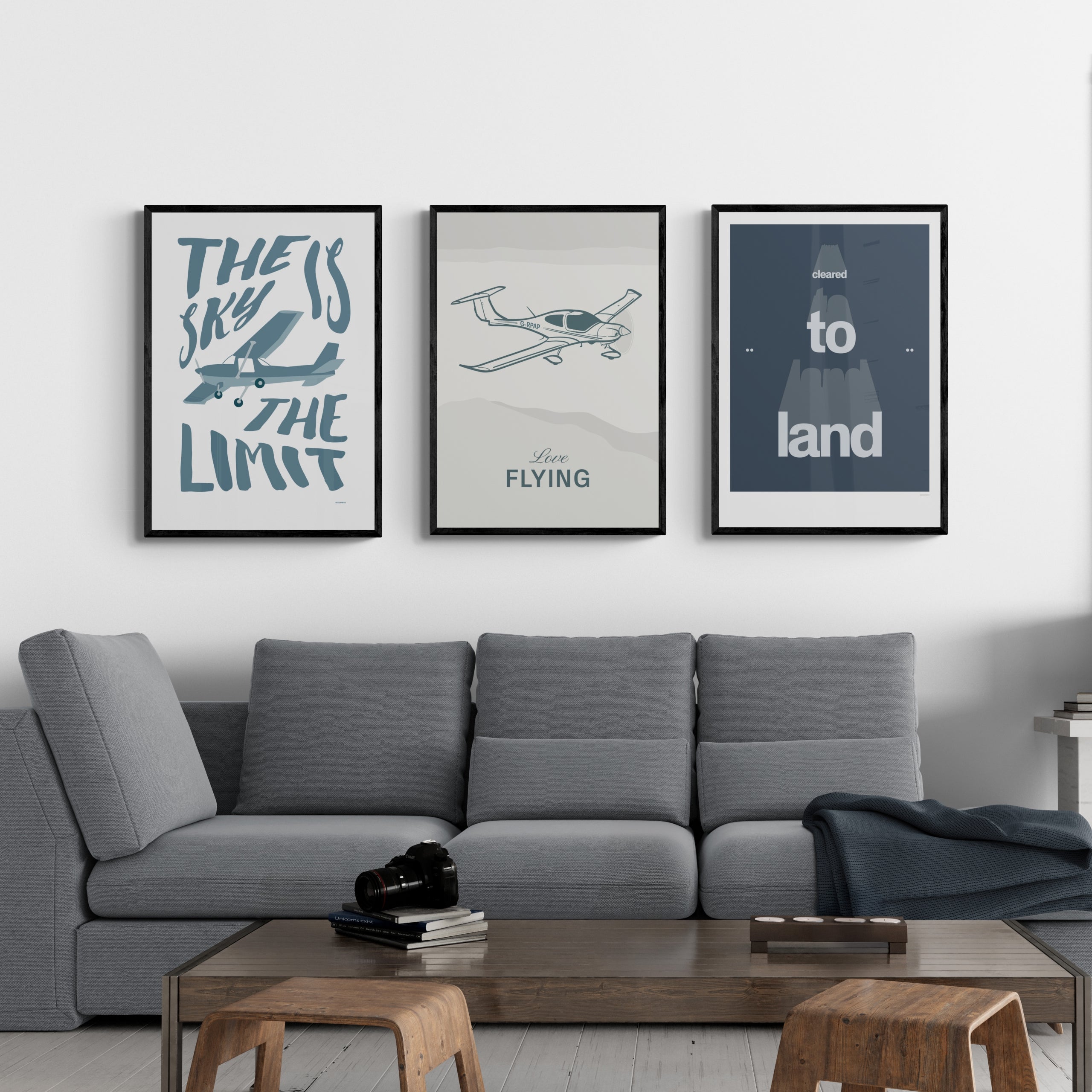Three framed prints hanging in a modern living room. The first shows an illustration of a light aircraft with the words the sky is the limit the second shows an illustration of a light aircraft with the words love flying the third shows a typographical position with the words cleared to land.