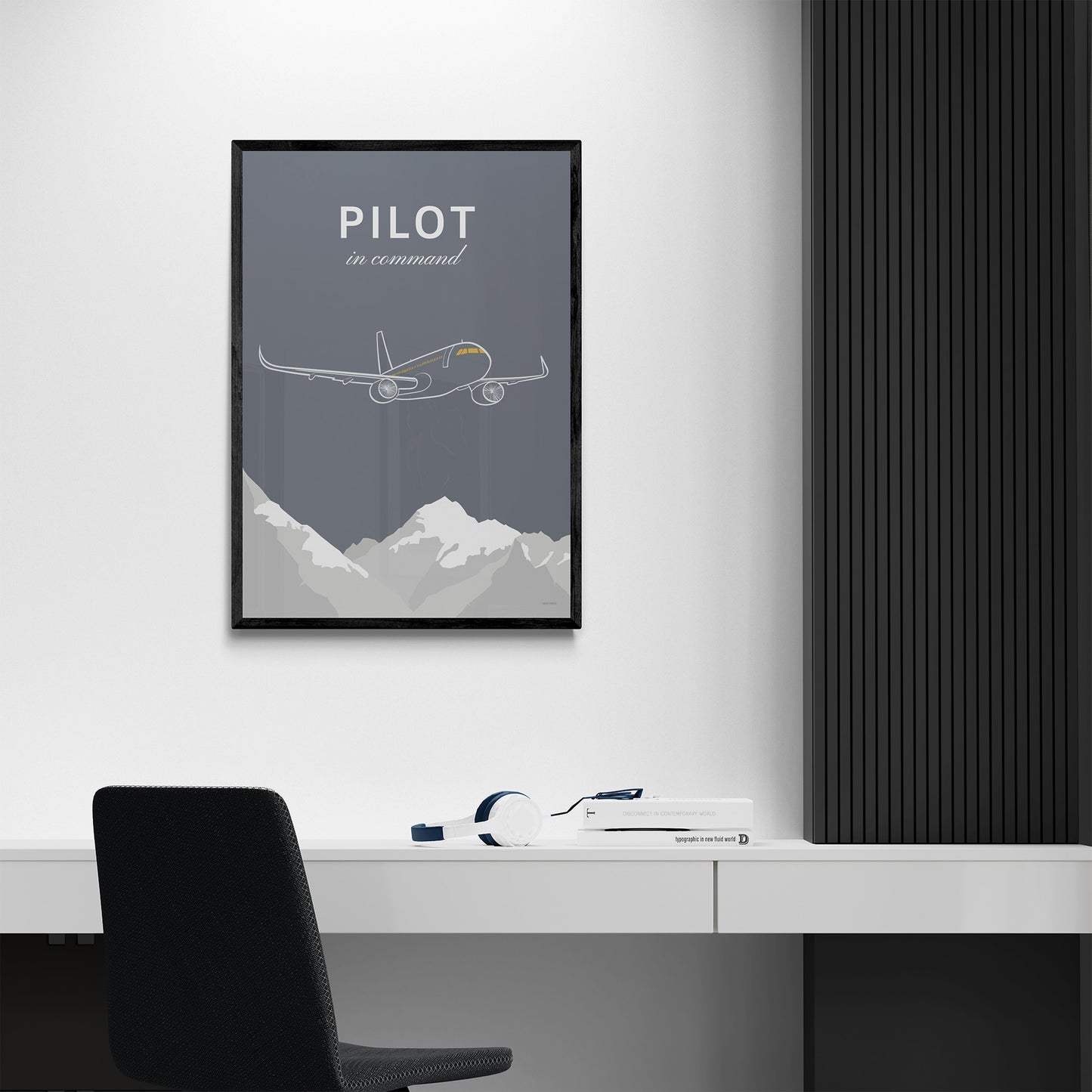 A frame to print hanging in a modern looking home office. It shows a white illustration of a passenger aircraft over mountains on a grey background and the words pilot in command