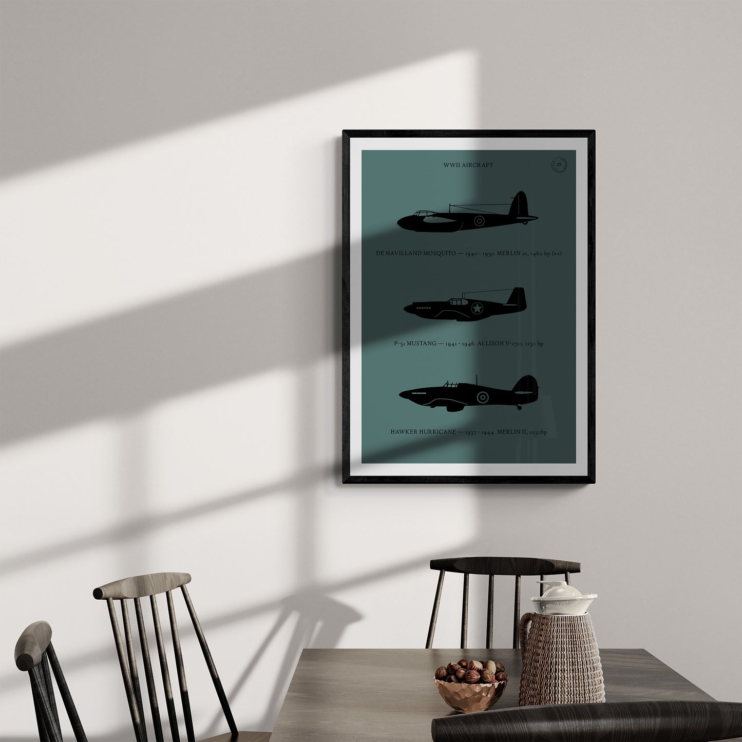 A framed poster hanging in a dining room over a dark wood table and chairs. It shows the profiles of three WW1 period aeroplanes in a black silhouette style over a dark green background