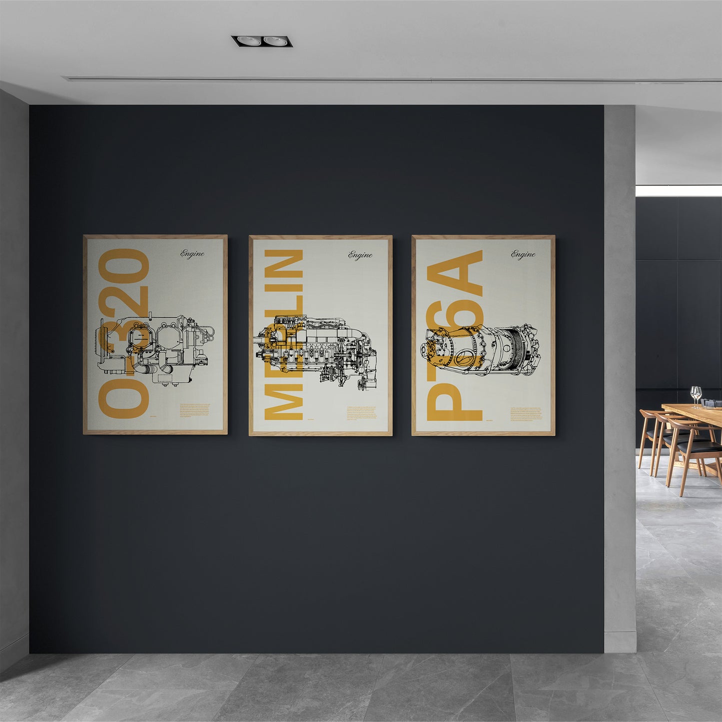 Three framed posters hanging in a dark grey wall in a modern house. In the background, a kitchen with a dining table and chairs. Each shows a famous aircraft engines in line drawing style, with the engine name written big in mustard yellow