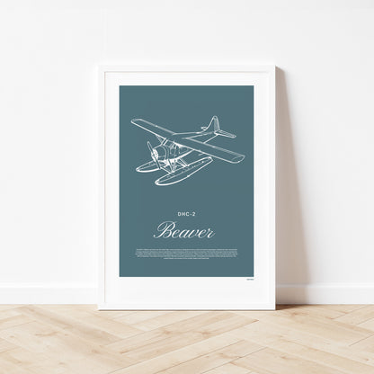 Framed poster standing on wood flooring, leaning against a white wall. It shows a light aircraft illustration with the words DHC-2 Beaver in white over a teal background