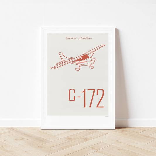 Framed poster standing on wood flooring, leaning against a white wall. It shows a light aircraft illustration with the words General Aviation and C-172 in red