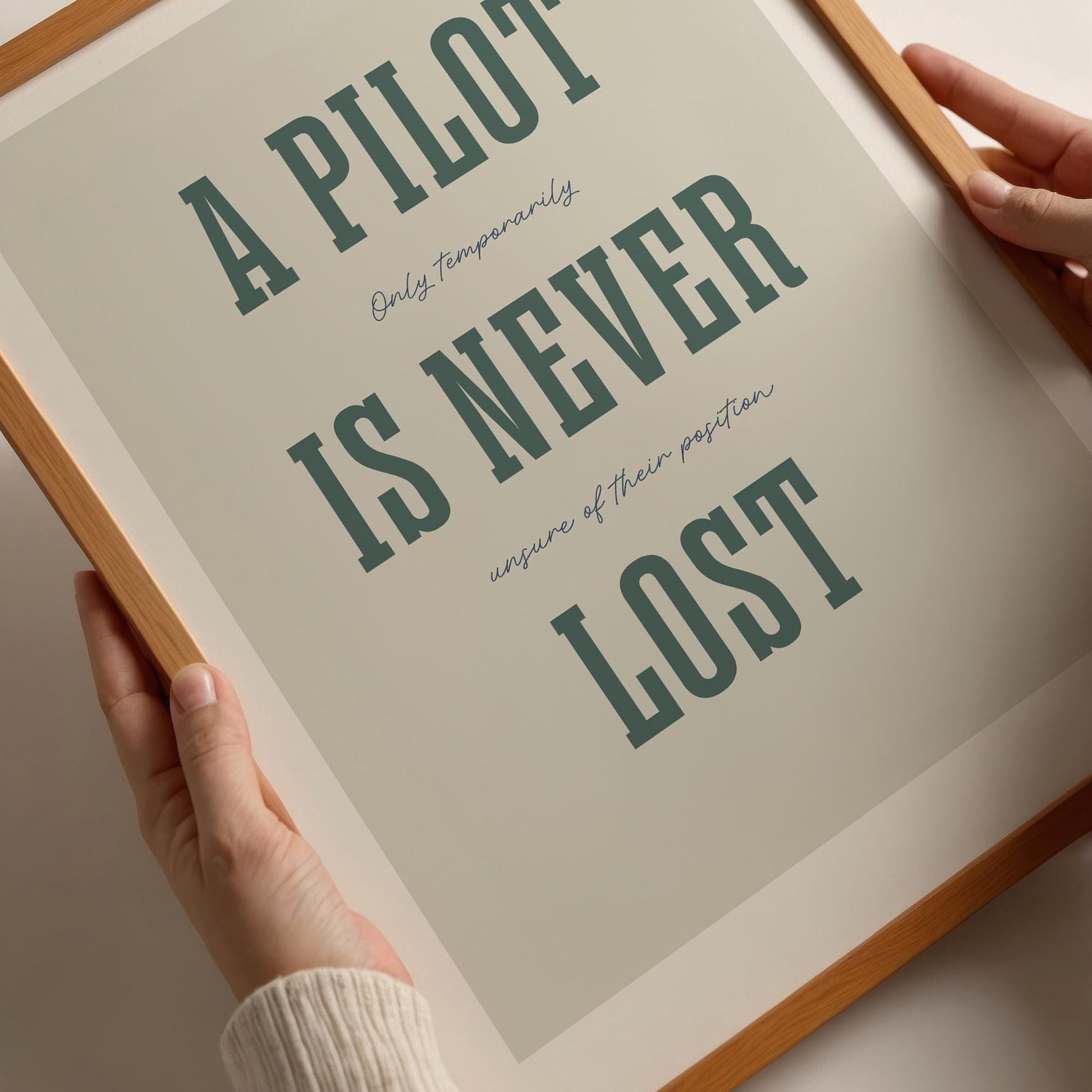 Closeup of a famed poster being held by a person. It shows the words - A Pilot Is Never Lost - in large green letters and the words - Only temporarily unsure of their position - in in black handwritten style