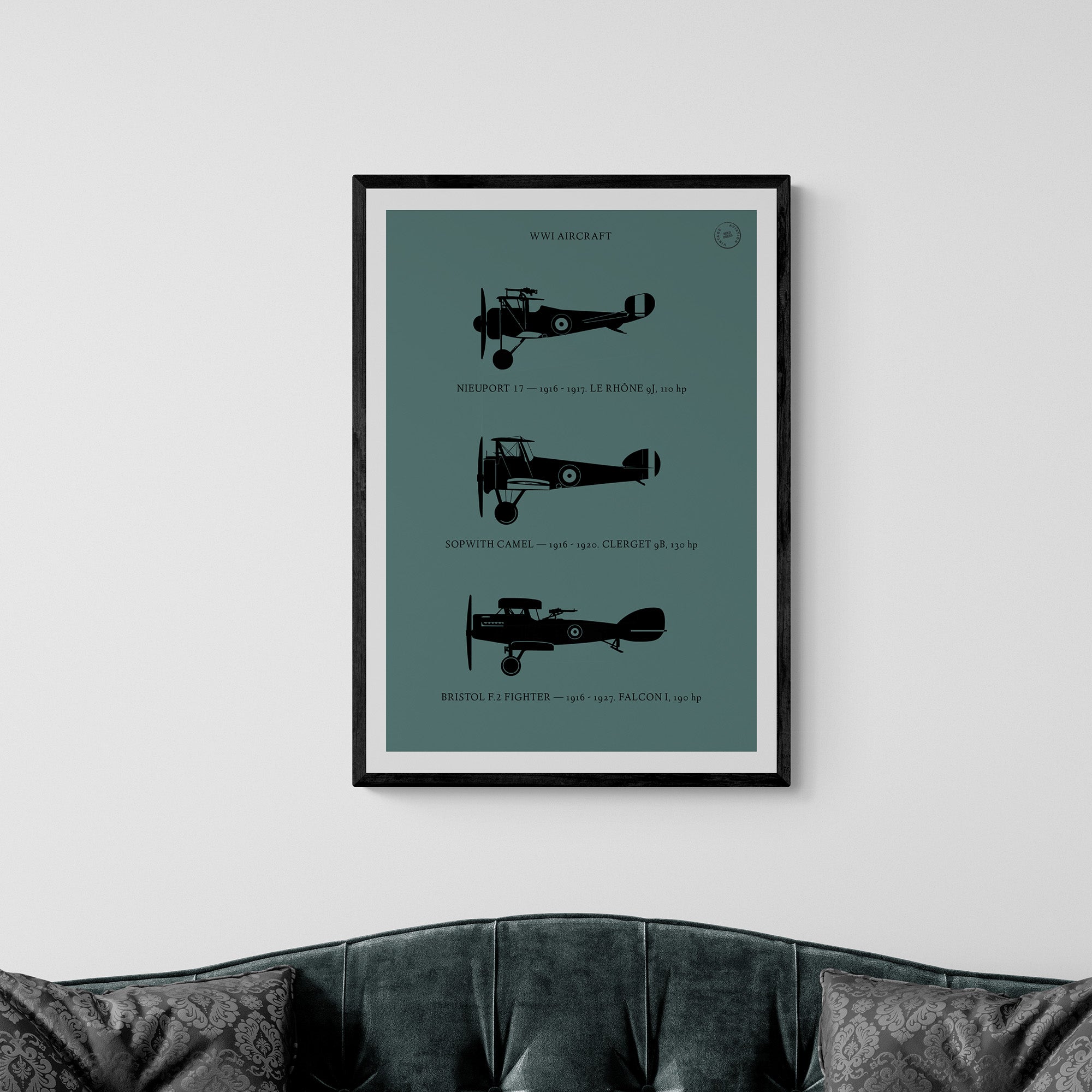 Close-up of a framed print hanging over a classic sofa. It shows the profiles of three WW1 period aeroplanes in a black silhouette style over a dark green background 