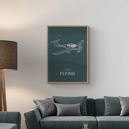 A framed print hanging on a living room over a green sofa. It shows a light aircraft illustration with the words Love Flying in white over a teal background