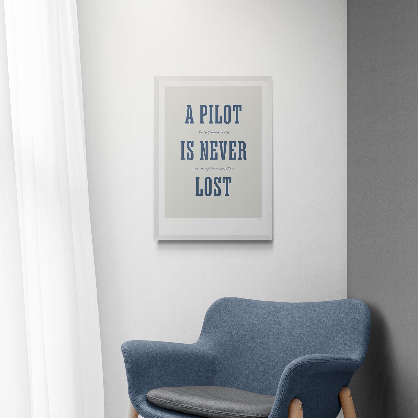 A framed print hanging over a blue chair. It shows the words - A Pilot Is Never Lost - in large blue letters and the words - Only temporarily unsure of their position - in in black handwritten style