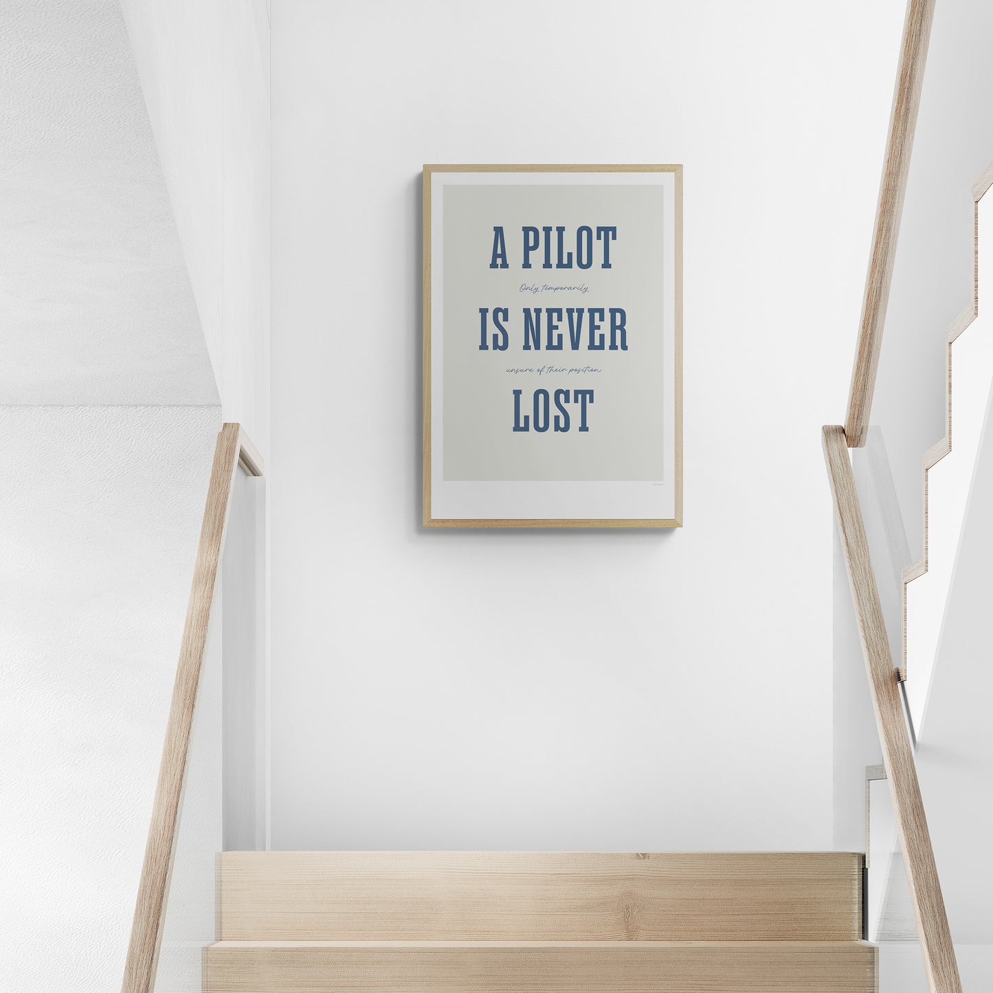 A framed print hanging in a staircase landing. It shows the words - A Pilot Is Never Lost - in large blue letters and the words - Only temporarily unsure of their position - in in black handwritten style