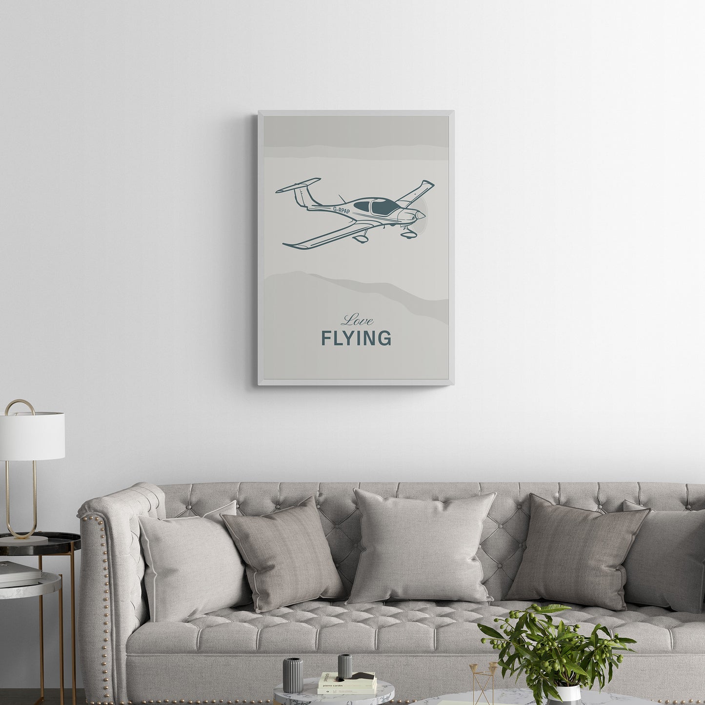 A framed print hanging on a luxurious living room. It shows a light aircraft illustration with the words Love Flying in white over an off white background