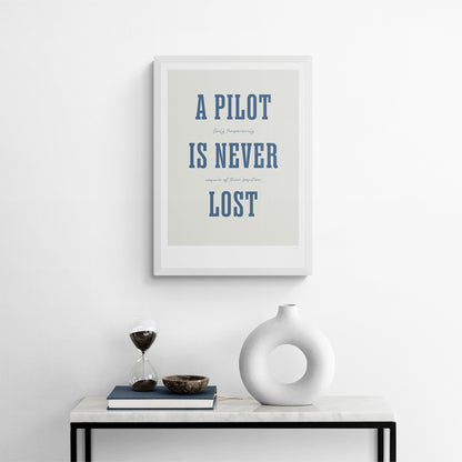 A framed print hanging over a console table. It shows the words - A Pilot Is Never Lost - in large blue letters and the words - Only temporarily unsure of their position - in in black handwritten style