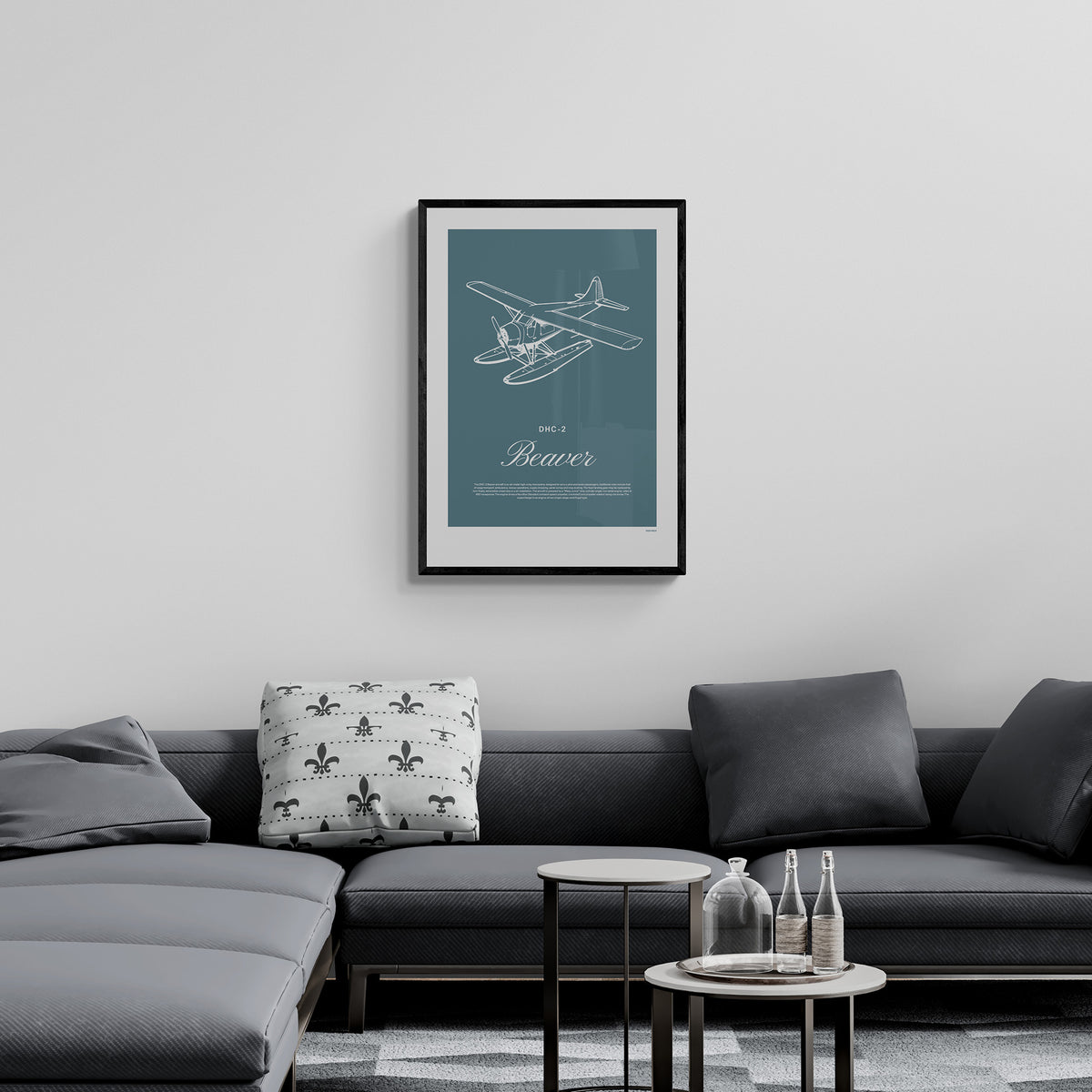 A framed print hanging in a living room, over a grey sofa. It shows a light aircraft illustration with the words DHC-2 Beaver in white over a teal background
